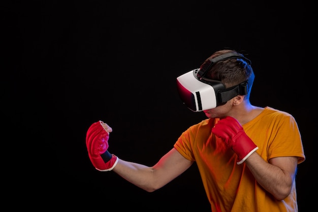 Hombre joven de boxeo en realidad virtual con guantes de mma en superficie negra