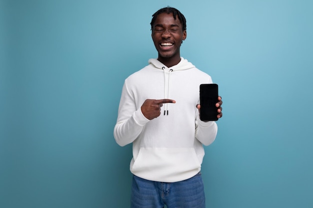 Hombre joven brunet americano muestra teléfono móvil desde maqueta de pantalla