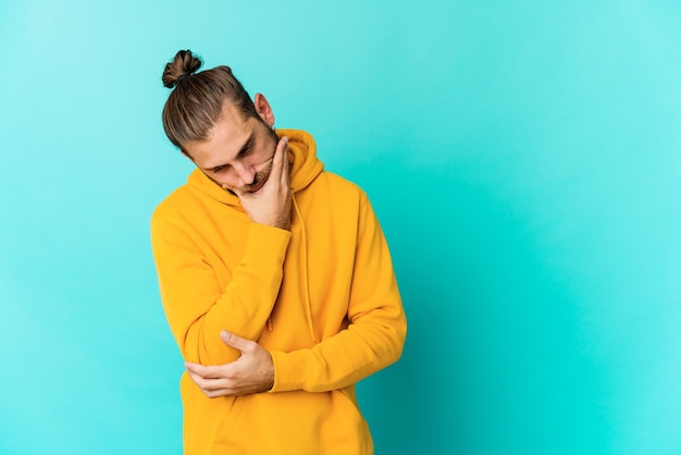 Foto hombre joven con cabello largo parece cansado de una tarea repetitiva.