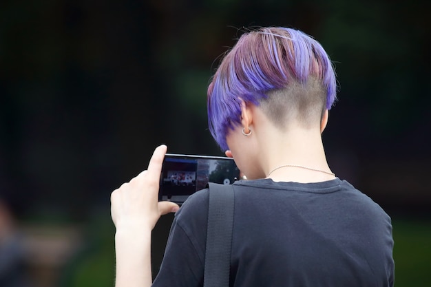 Hombre joven con cabello teñido graba un video usando un evento de teléfono inteligente