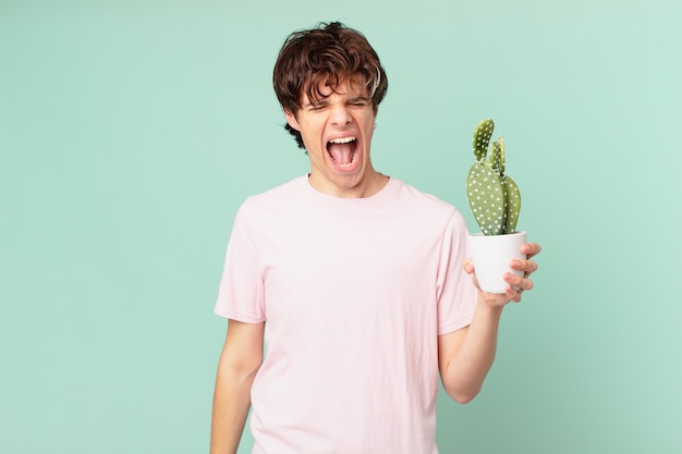 Hombre joven con un cactus gritando agresivamente, luciendo muy enojado