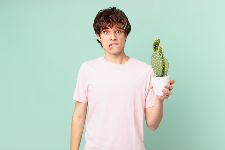 Foto hombre joven con un cactus mirando perplejo y confundido