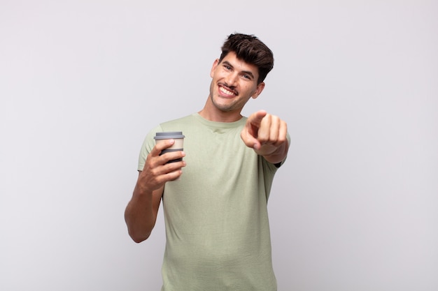 Foto hombre joven con un café apuntando a la cámara con una sonrisa satisfecha