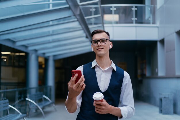 Hombre joven con un café para llevar hablando por un enlace de video.