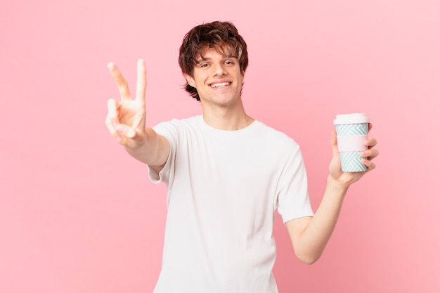 Hombre joven con un café sonriendo y mirando feliz, gesticulando victoria o paz