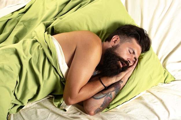 Hombre joven en la cama tratando de dormir Hombre guapo duerme en el dormitorio acostado en la cama Necesita descansar