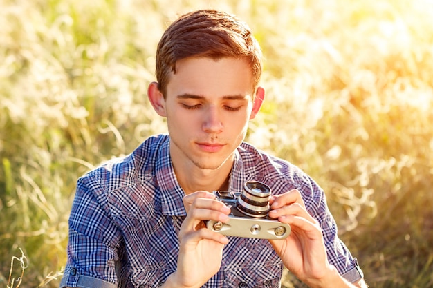 un hombre joven con una cámara que toma imágenes del fondo natural rayos de sol teñidos
