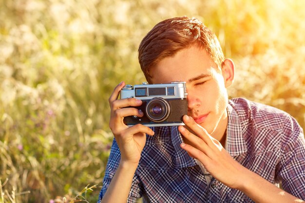 un hombre joven con una cámara que toma imágenes del fondo natural rayos de sol teñidos