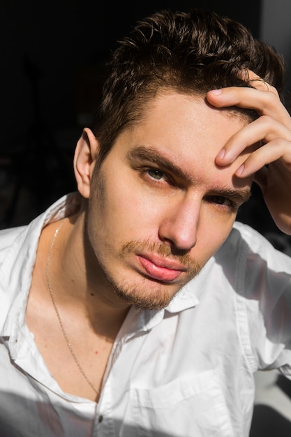 Hombre joven en camisa blanca sobre fondo oscuro. Empresario y emprendedor. Modelo