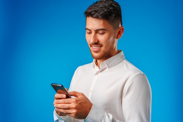 Hombre joven con camisa blanca con su smartphone