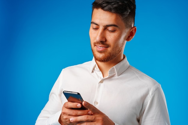 Hombre joven con camisa blanca con su smartphone