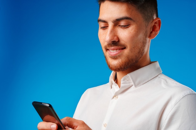 Hombre joven con camisa blanca con su smartphone