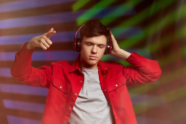 Hombre joven en camisa roja con auriculares escuchando música