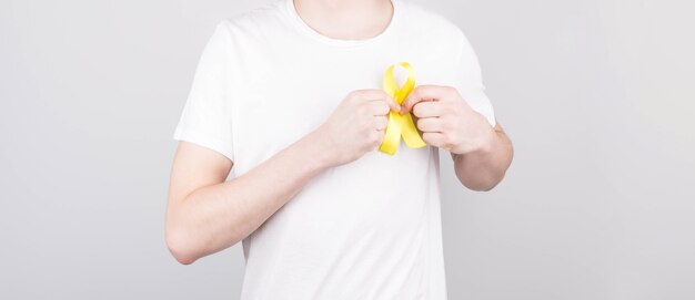 Hombre joven en camiseta blanca con símbolo de conciencia de cinta amarilla para el suicidio