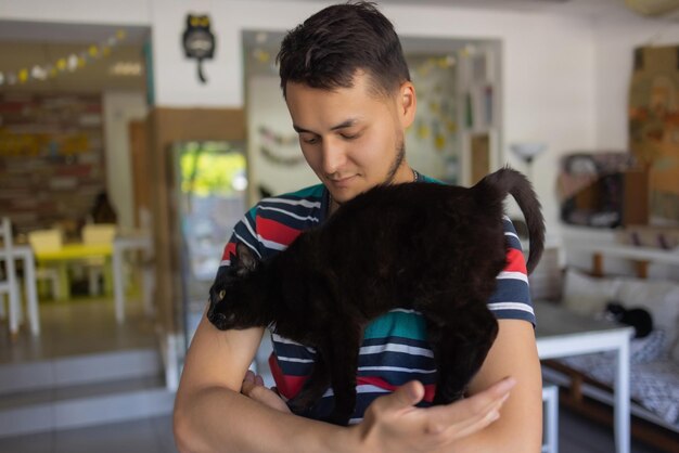 Hombre joven en camiseta sosteniendo un gato