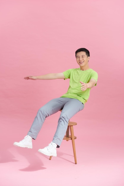 Un hombre joven con una camiseta verde está sentado en una silla alta.
