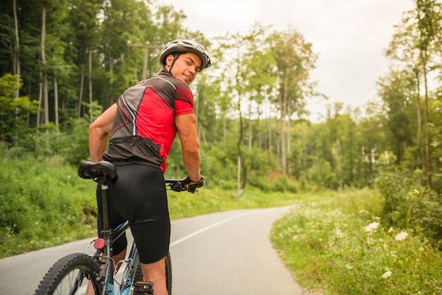 Hombre joven en casco montando en bicicleta de montaña.