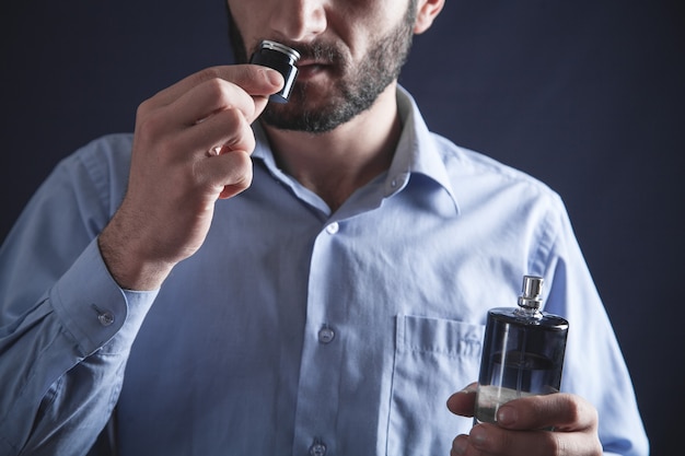 Hombre joven caucásico que huele el perfume.