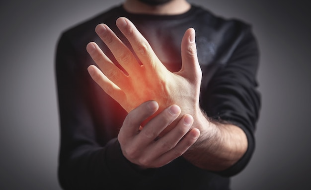 Hombre joven caucásico que tiene dolor en la mano.