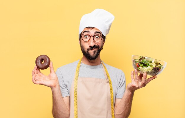 Hombre joven chef barbudo dudando o expresión incierta