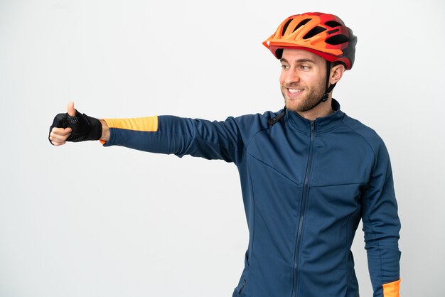 Hombre joven ciclista aislado en la pared blanca dando un pulgar hacia arriba gesto