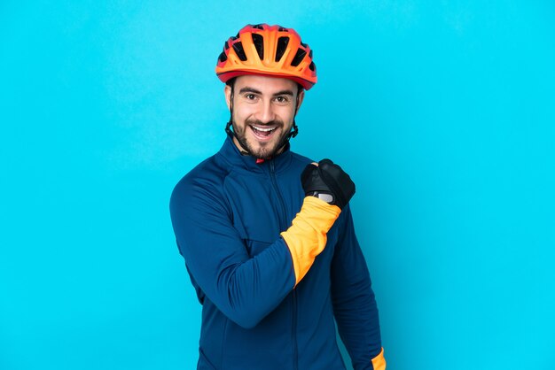 Hombre joven ciclista aislado sobre fondo azul celebrando una victoria