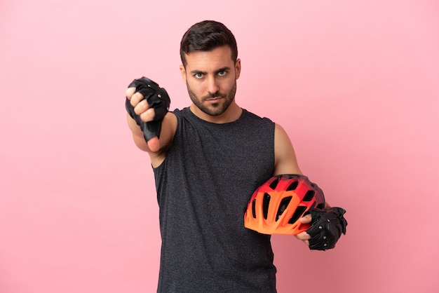 Hombre joven ciclista aislado sobre fondo rosa que muestra el pulgar hacia abajo con expresión negativa