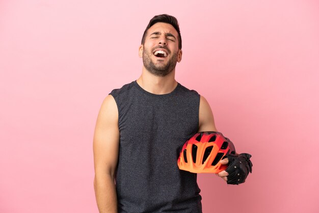 Hombre joven ciclista aislado sobre fondo rosa riendo