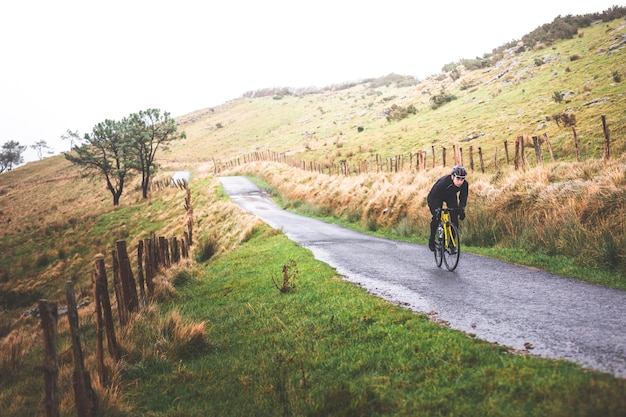 Hombre joven ciclista caucásico subiendo una colina en una montaña de niebla.