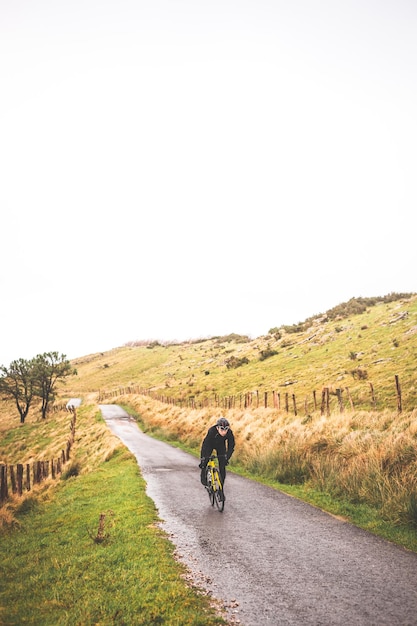 Foto hombre joven ciclista caucásico subiendo una colina en una montaña de niebla.