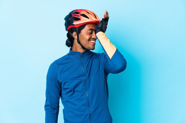 Hombre joven ciclista con trenzas sobre pared aislada se ha dado cuenta de algo y tiene la intención de la solución