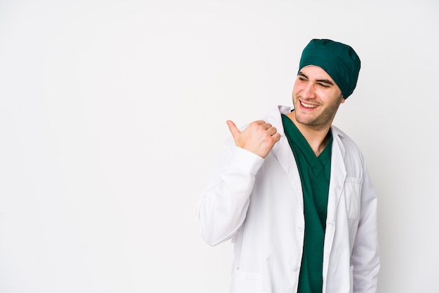 Foto hombre joven cirujano apunta con el dedo pulgar lejos