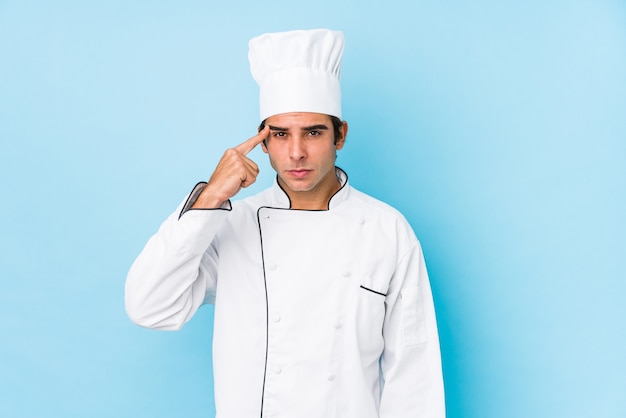 Hombre joven cocinero aislado mostrando un gesto de decepción con el dedo índice.