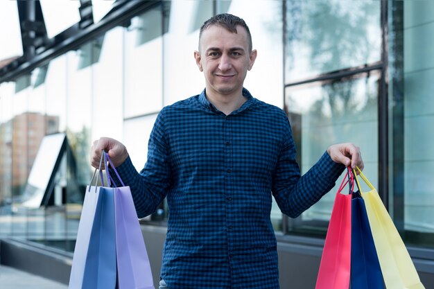 Hombre joven con coloridos bolsos de compras en la calle.