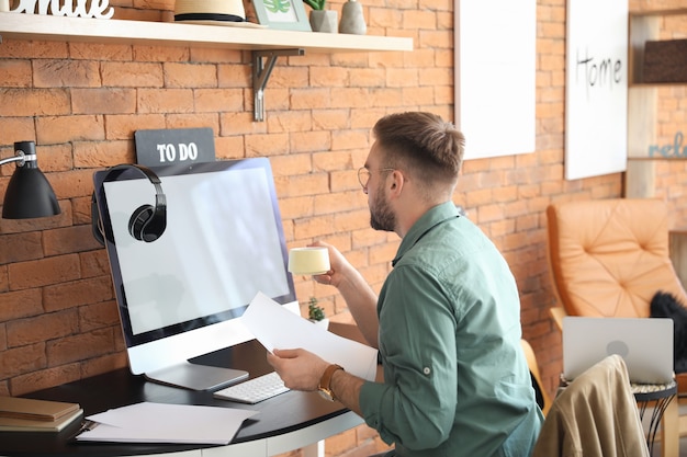 Hombre joven con computadora trabajando en casa