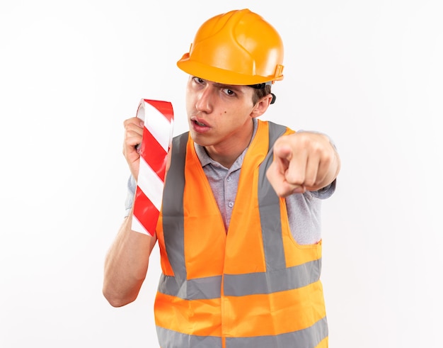 Foto hombre joven constructor estricto en uniforme sosteniendo cinta adhesiva que le muestra gesto