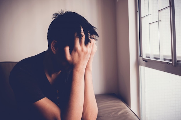 Foto hombre joven deprimido, desesperado y ansioso sentado solo en casa, salud mental, concepto de salud masculina