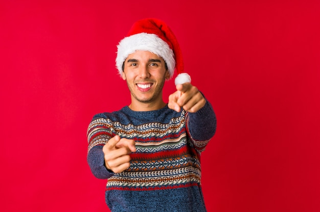 Hombre joven en el día de navidad con el ceño fruncido, disgustado, mantiene los brazos cruzados.