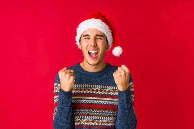 Hombre joven el día de Navidad cubriendo las orejas con las manos.