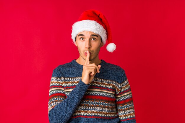 Hombre joven el día de Navidad divirtiéndose cubriendo la mitad de la cara con la palma.