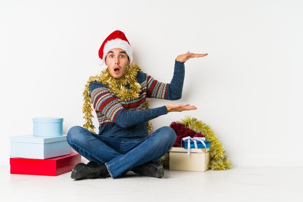 Hombre joven el día de Navidad con un espacio de copia en una palma.