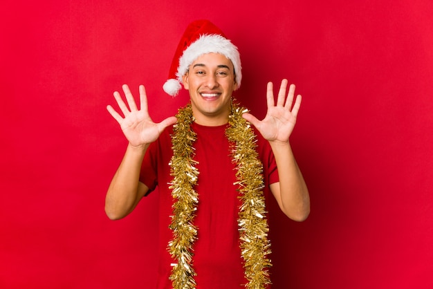 Hombre joven el día de Navidad que muestra el número diez con las manos.