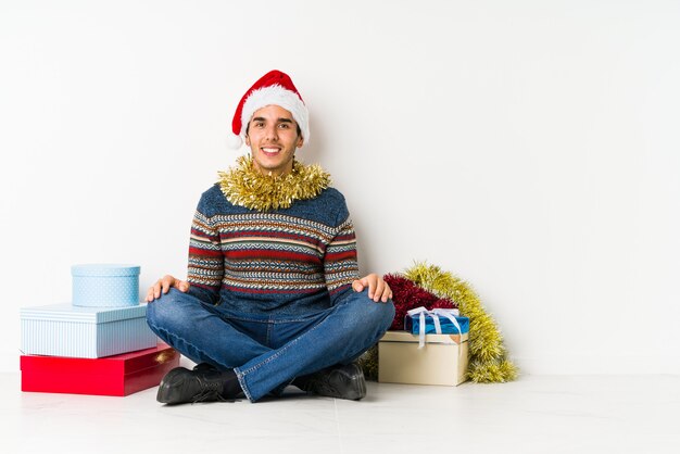 Hombre joven el día de Navidad que se siente triste y pensativo, mirando el espacio de la copia.