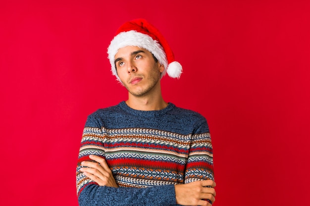 Hombre joven el día de Navidad sonriendo y mostrando una forma de corazón con las manos.