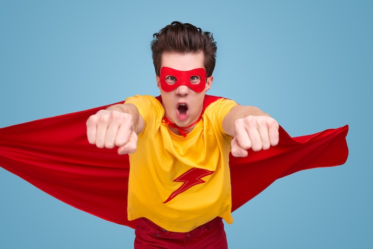 Foto hombre joven divertido en traje de superhéroe rugiendo y volando hacia la cámara mientras salva el mundo contra el fondo azul