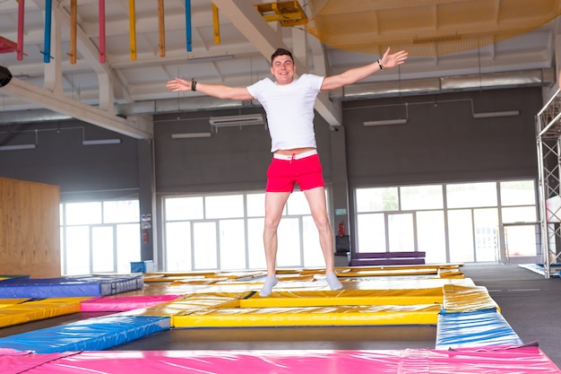 Hombre joven divertido trampolín en el parque de moscas.