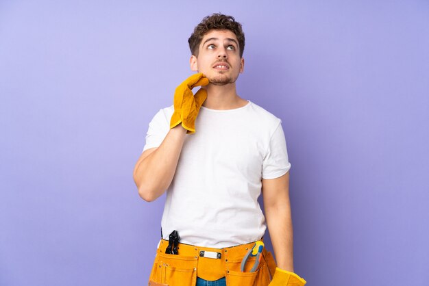 Hombre joven electricista aislado sobre pared púrpura pensando en una idea