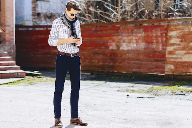 Foto hombre joven elegante en gafas de sol con el teléfono en la calle