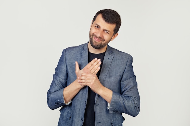 Hombre joven empresario con barba en una chaqueta, que sufre de dolor en las manos y los dedos, inflamación de la artritis.