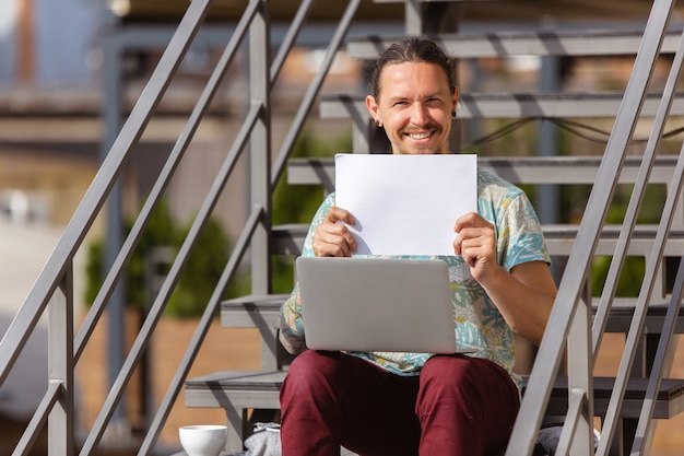 Hombre joven, empresario en busca de trabajo con portátil al aire libre,